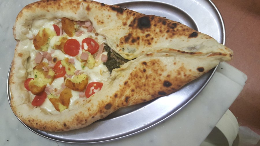 Calzone de Lo Scugnizzo semiaperto con mozzarella, pomodorini, crocchette, prosciutto a dadini, su vassoio d'acciaio