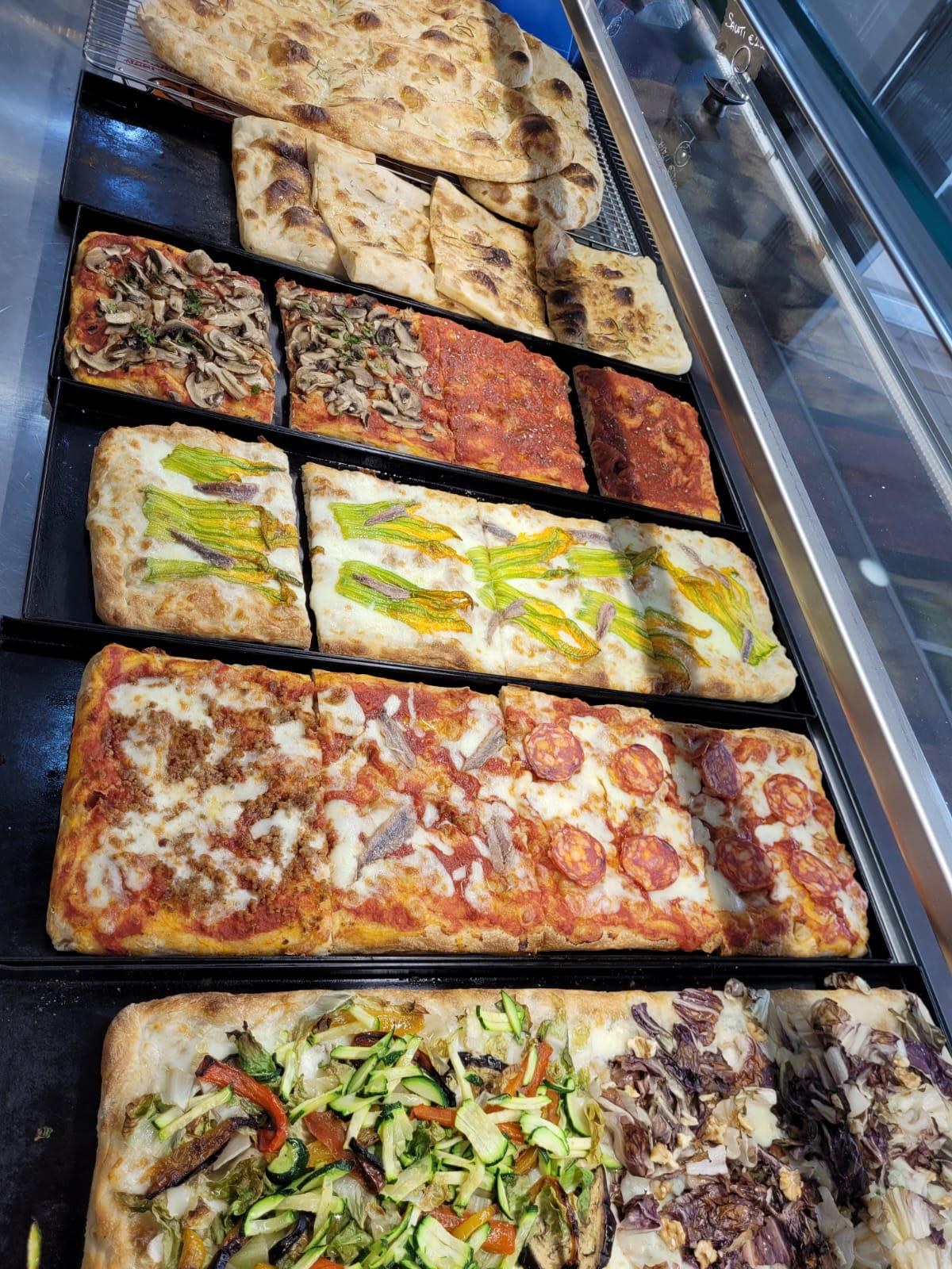 Pizza al taglio in vetrina da Lo Scugnizzo: teglie con funghi, salame piccante, alici, radicchio, zucchine e focaccia