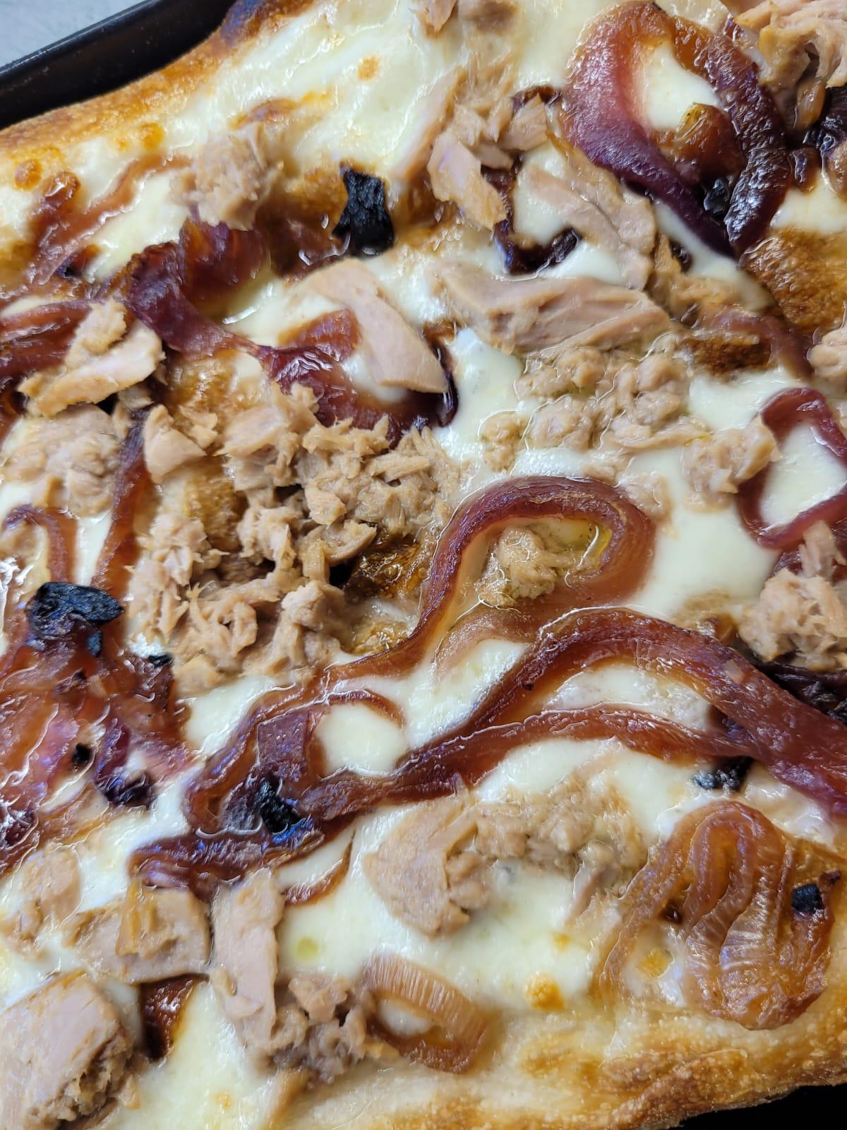 Pizza in teglia con mozzarella fusa, tonno sbriciolato e cipolle rosse caramellate su bordo dorato, Lo Scugnizzo